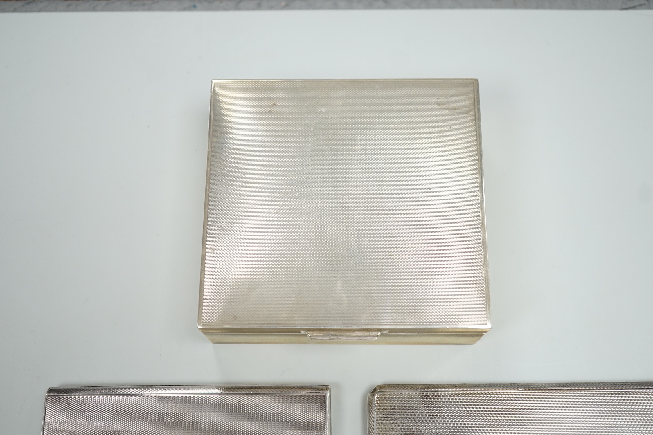 Two 1930's/1940's engine turned silver cigarette cases, largest 14cm and a later silver mounted cigarette box.
